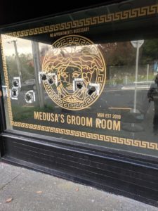 Hair-dresser's glass shop front, gold writing "Medua's Groom Room" and 8 large projectile holes with Police measurement markings.